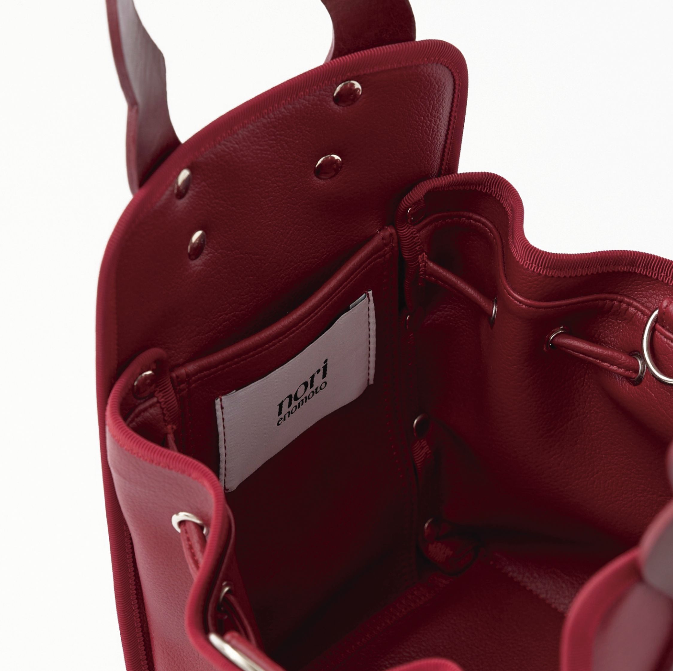 本革ハンドルの巾着型ハンドバッグ。サイドのドローストリングでシルエットを変化可能。500mlペットボトル対応サイズで内ポケット付き。取り外し可能なチェーンストラップでショルダー・クロスボディ両用。