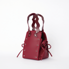 本革ハンドルの巾着型ハンドバッグ。サイドのドローストリングでシルエットを変化可能。500mlペットボトル対応サイズで内ポケット付き。取り外し可能なチェーンストラップでショルダー・クロスボディ両用。