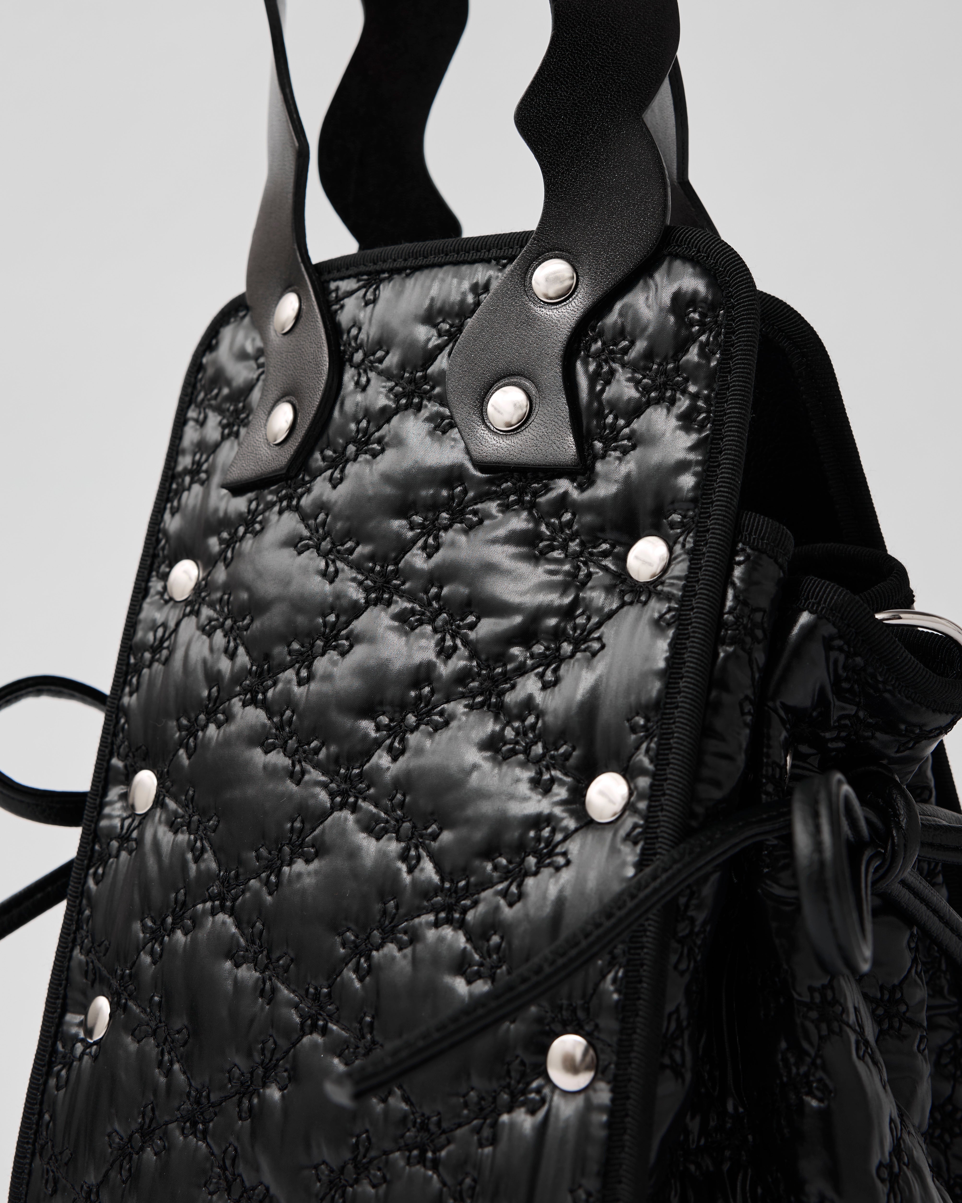 本革ハンドルの巾着型ハンドバッグ。サイドのドローストリングでシルエットを変化可能。500mlペットボトル対応サイズで内ポケット付き。取り外し可能なチェーンストラップでショルダー・クロスボディ両用。