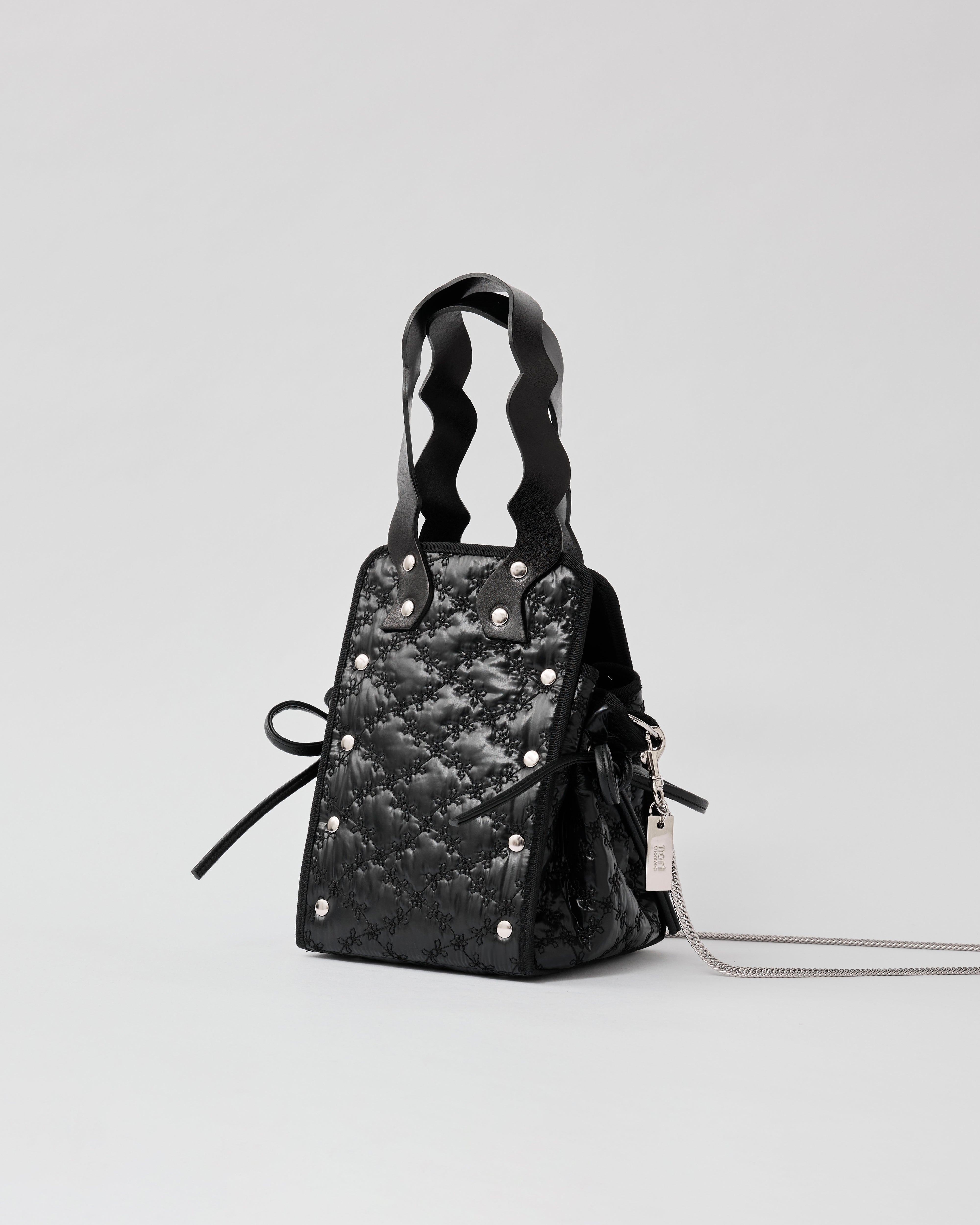 本革ハンドルの巾着型ハンドバッグ。サイドのドローストリングでシルエットを変化可能。500mlペットボトル対応サイズで内ポケット付き。取り外し可能なチェーンストラップでショルダー・クロスボディ両用。