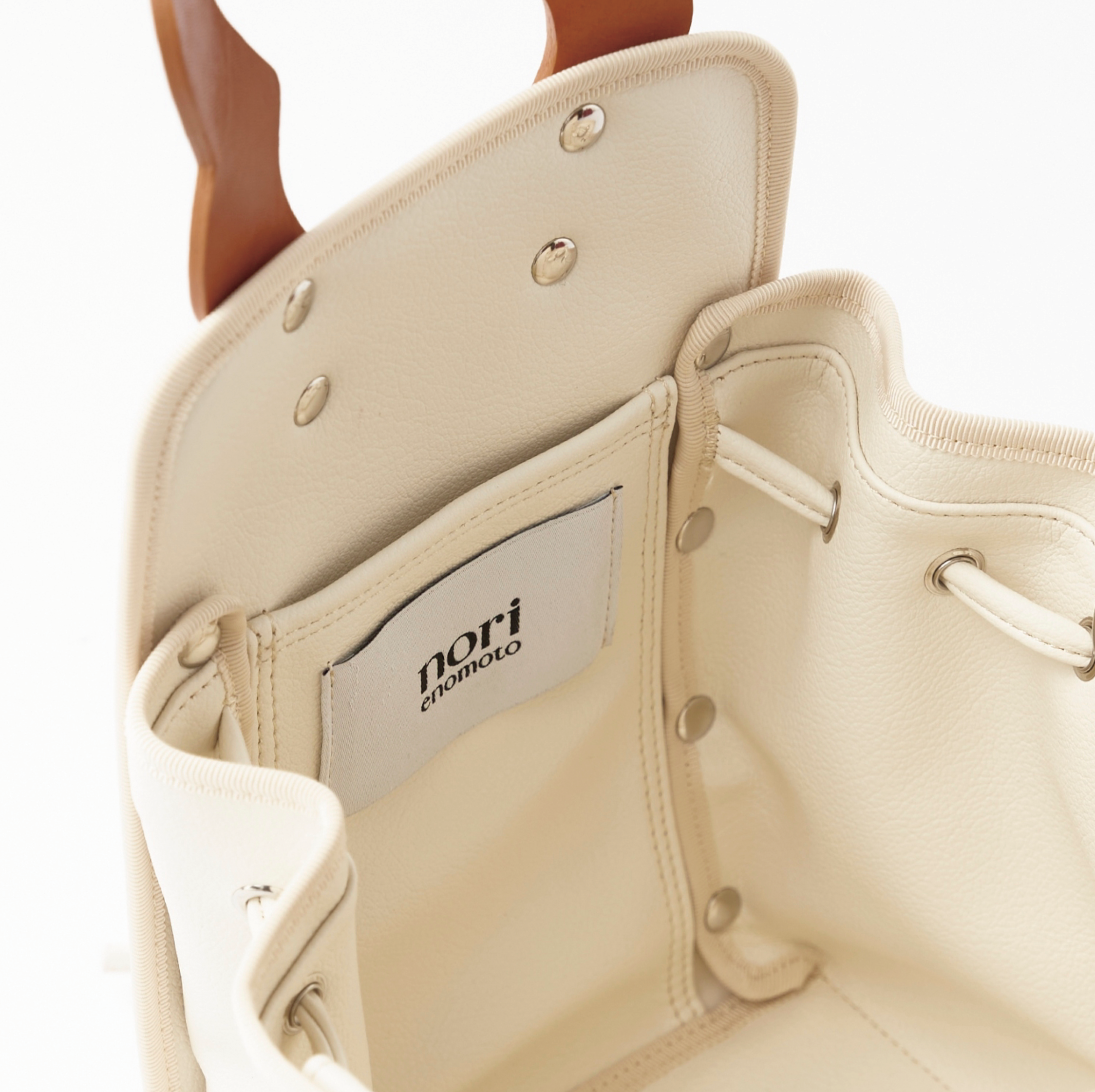 本革ハンドルの巾着型ハンドバッグ。サイドのドローストリングでシルエットを変化可能。500mlペットボトル対応サイズで内ポケット付き。取り外し可能なチェーンストラップでショルダー・クロスボディ両用。