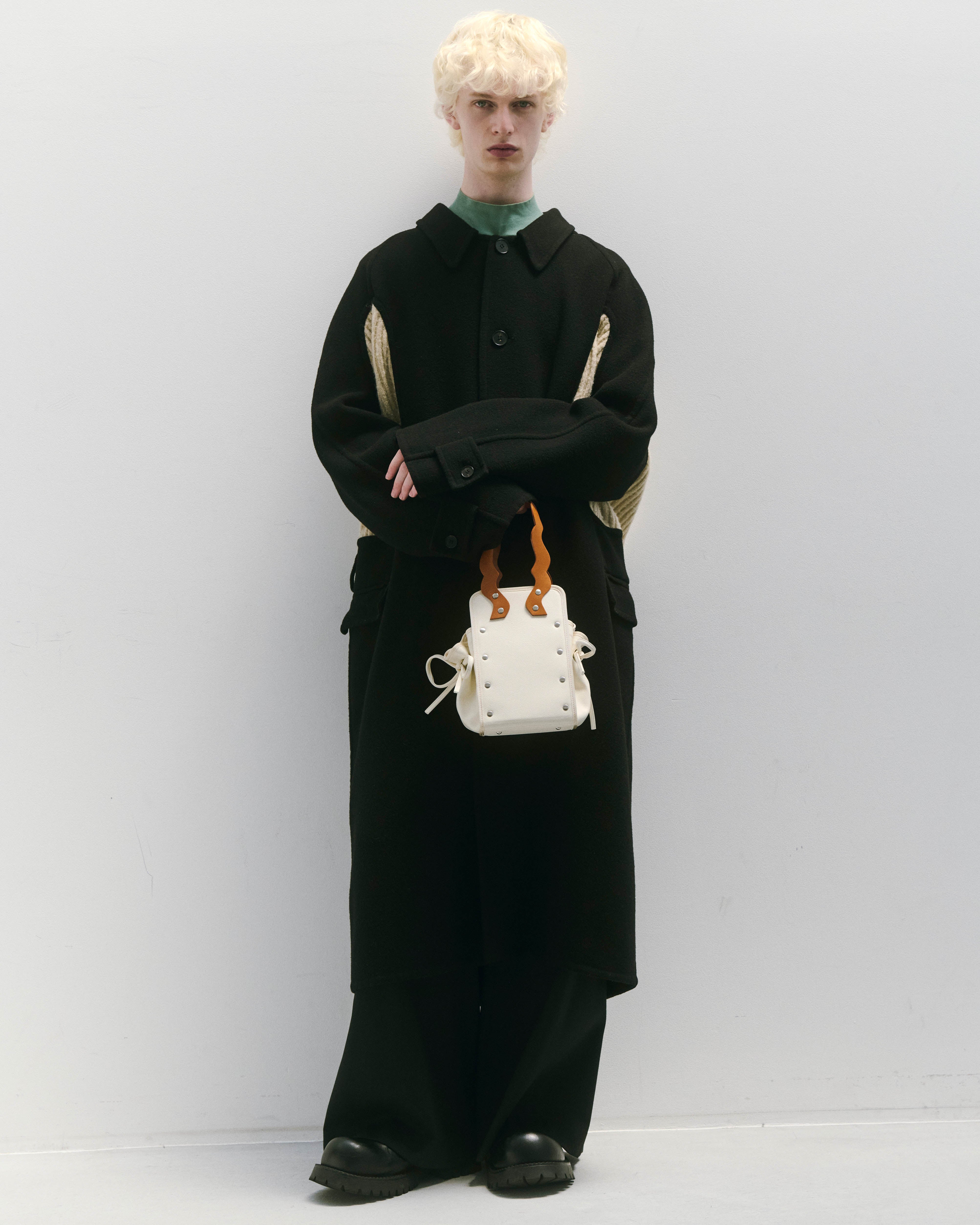 本革ハンドルの巾着型ハンドバッグ。サイドのドローストリングでシルエットを変化可能。500mlペットボトル対応サイズで内ポケット付き。取り外し可能なチェーンストラップでショルダー・クロスボディ両用。