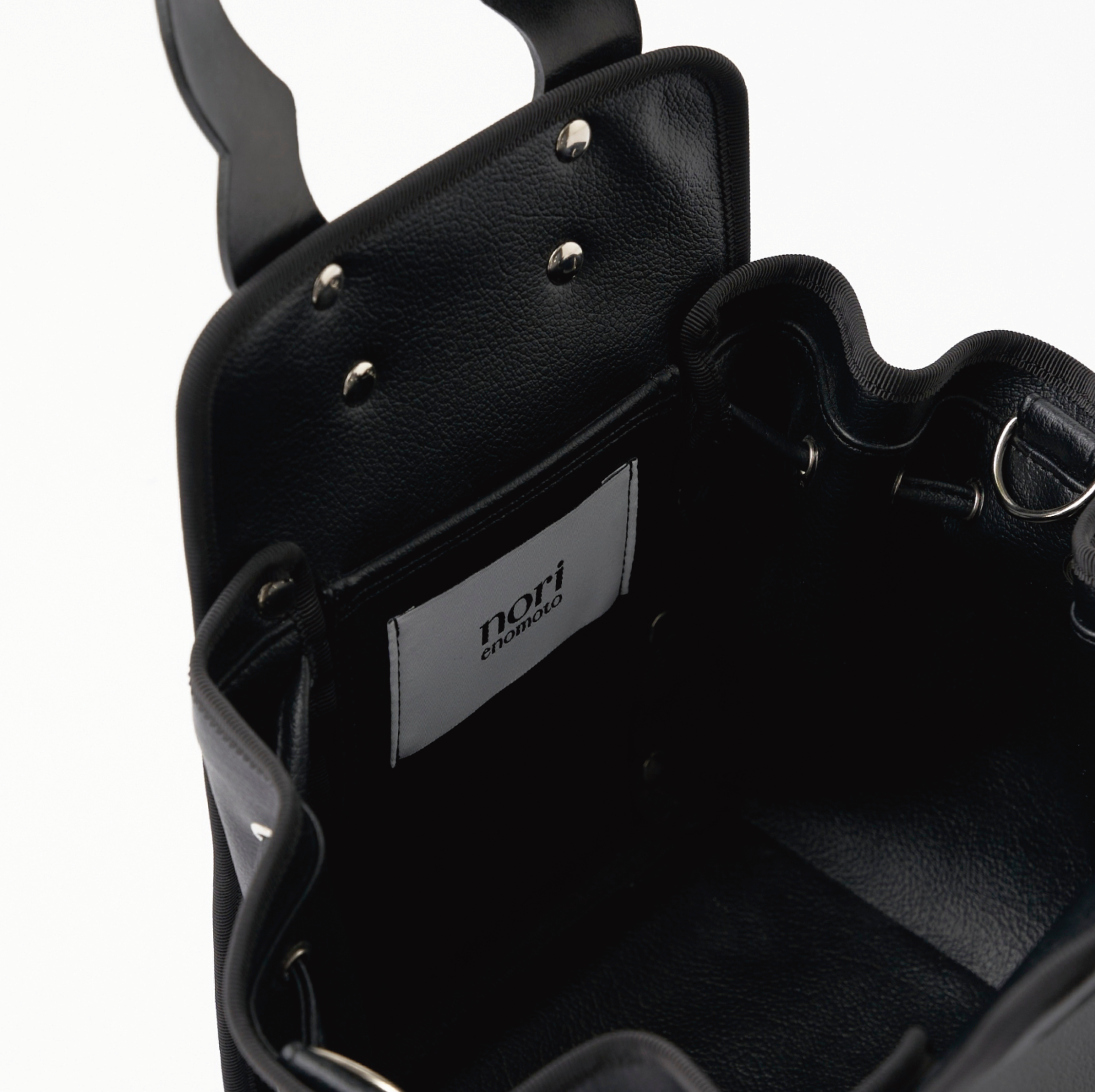 本革ハンドルの巾着型ハンドバッグ。サイドのドローストリングでシルエットを変化可能。500mlペットボトル対応サイズで内ポケット付き。取り外し可能なチェーンストラップでショルダー・クロスボディ両用。