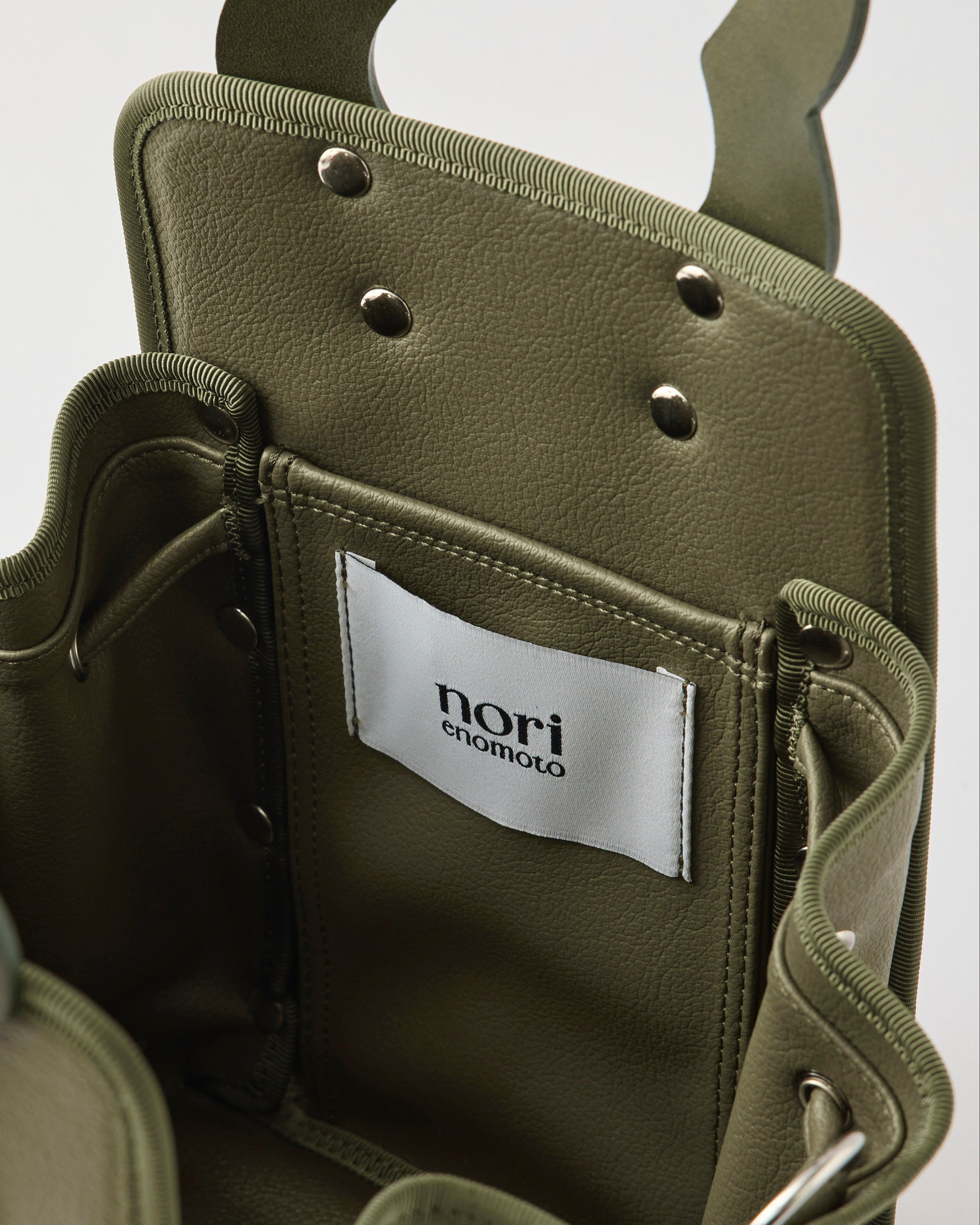 本革ハンドルの巾着型ハンドバッグ。サイドのドローストリングでシルエットを変化可能。500mlペットボトル対応サイズで内ポケット付き。取り外し可能なチェーンストラップでショルダー・クロスボディ両用。