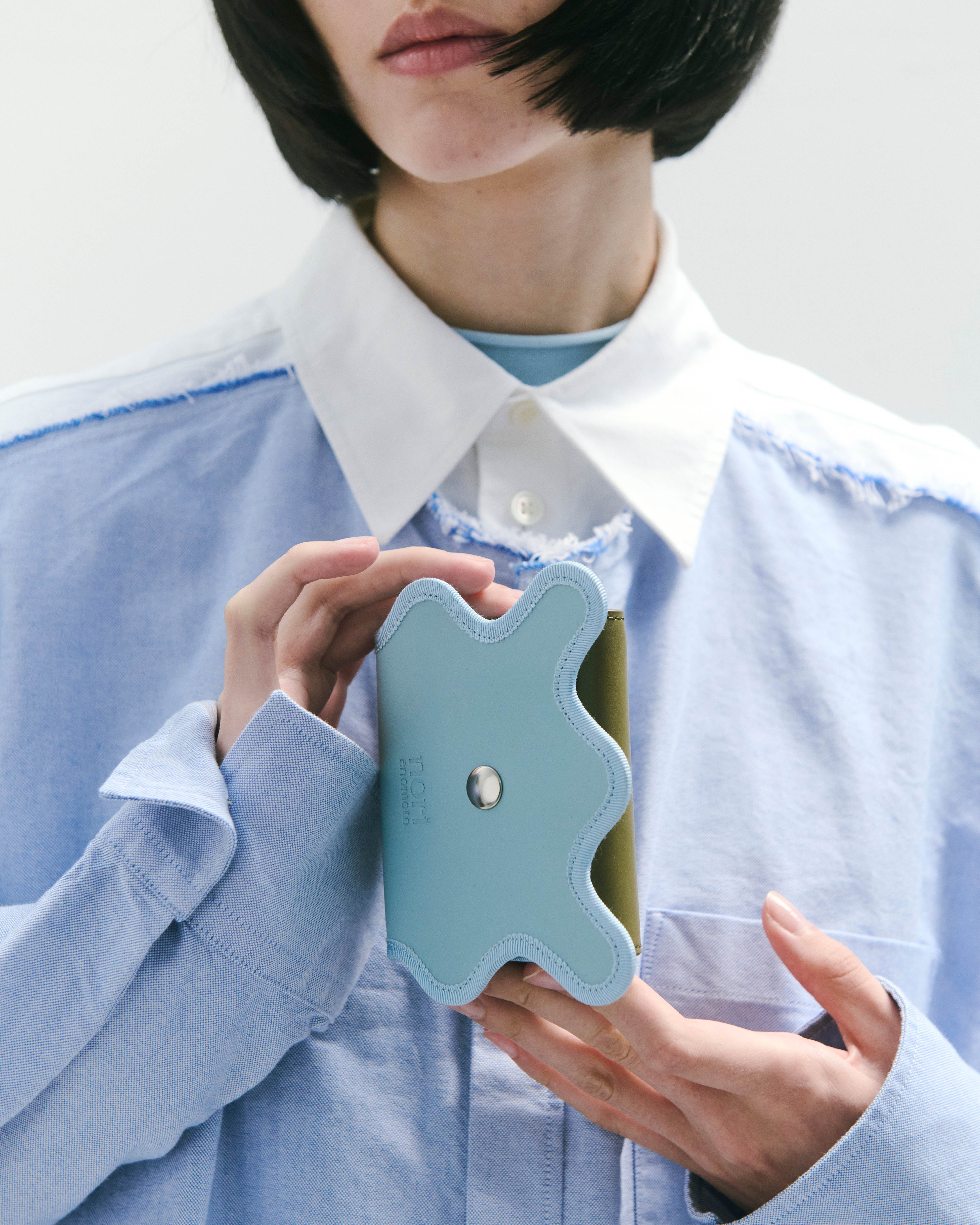 nori enomoto wave trifold wallet 表面にエンボスロゴを施した本革製の三つ折り財布。小銭入れ、紙幣ポケット、カードスリットを備えた実用的なレザーウォレット。