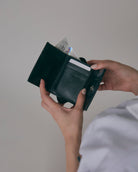 nori enomoto wave trifold wallet 表面にエンボスロゴを施した本革製の三つ折り財布。小銭入れ、紙幣ポケット、カードスリットを備えた実用的なレザーウォレット。