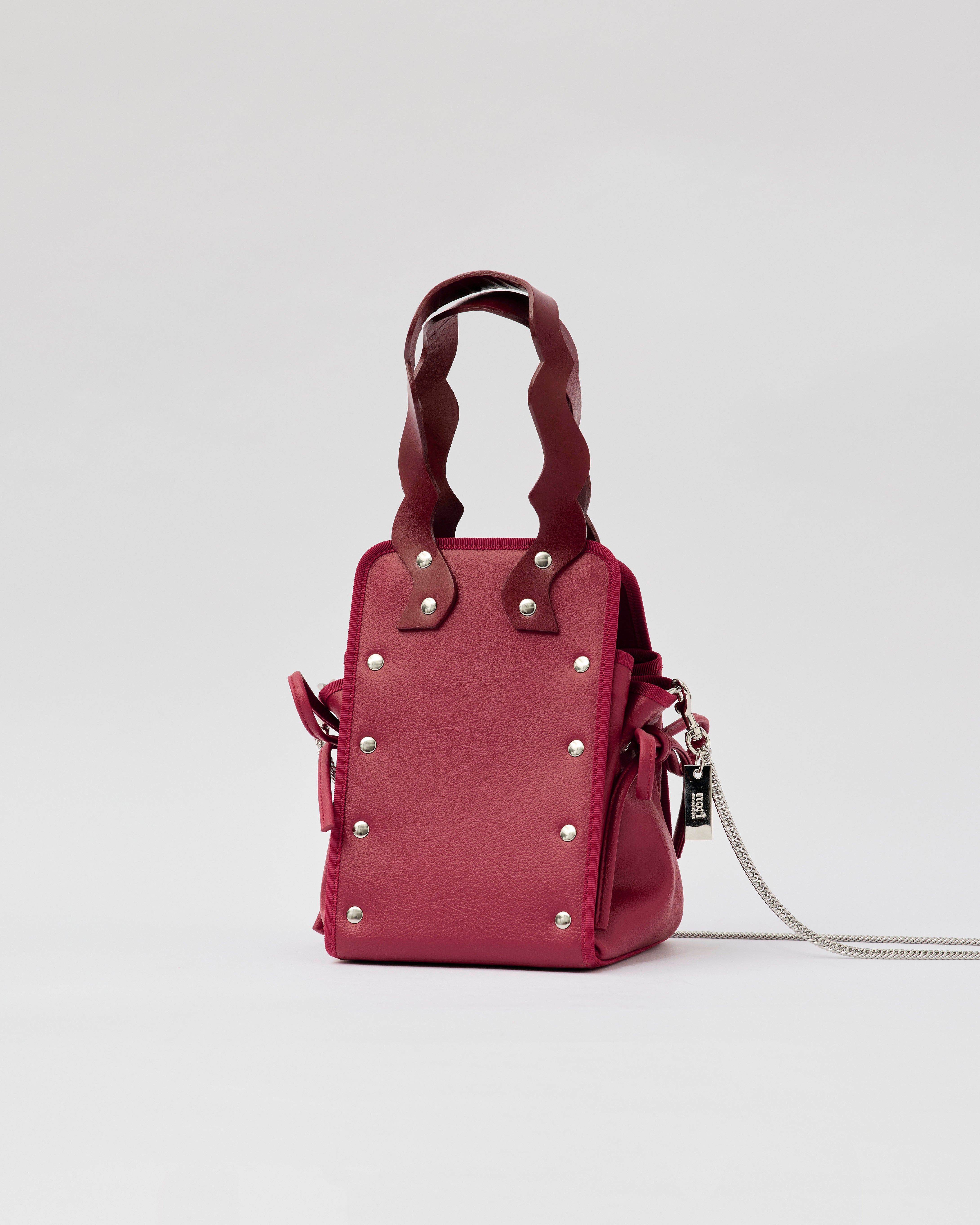 本革ハンドルの巾着型ハンドバッグ。サイドのドローストリングでシルエットを変化可能。500mlペットボトル対応サイズで内ポケット付き。取り外し可能なチェーンストラップでショルダー・クロスボディ両用。