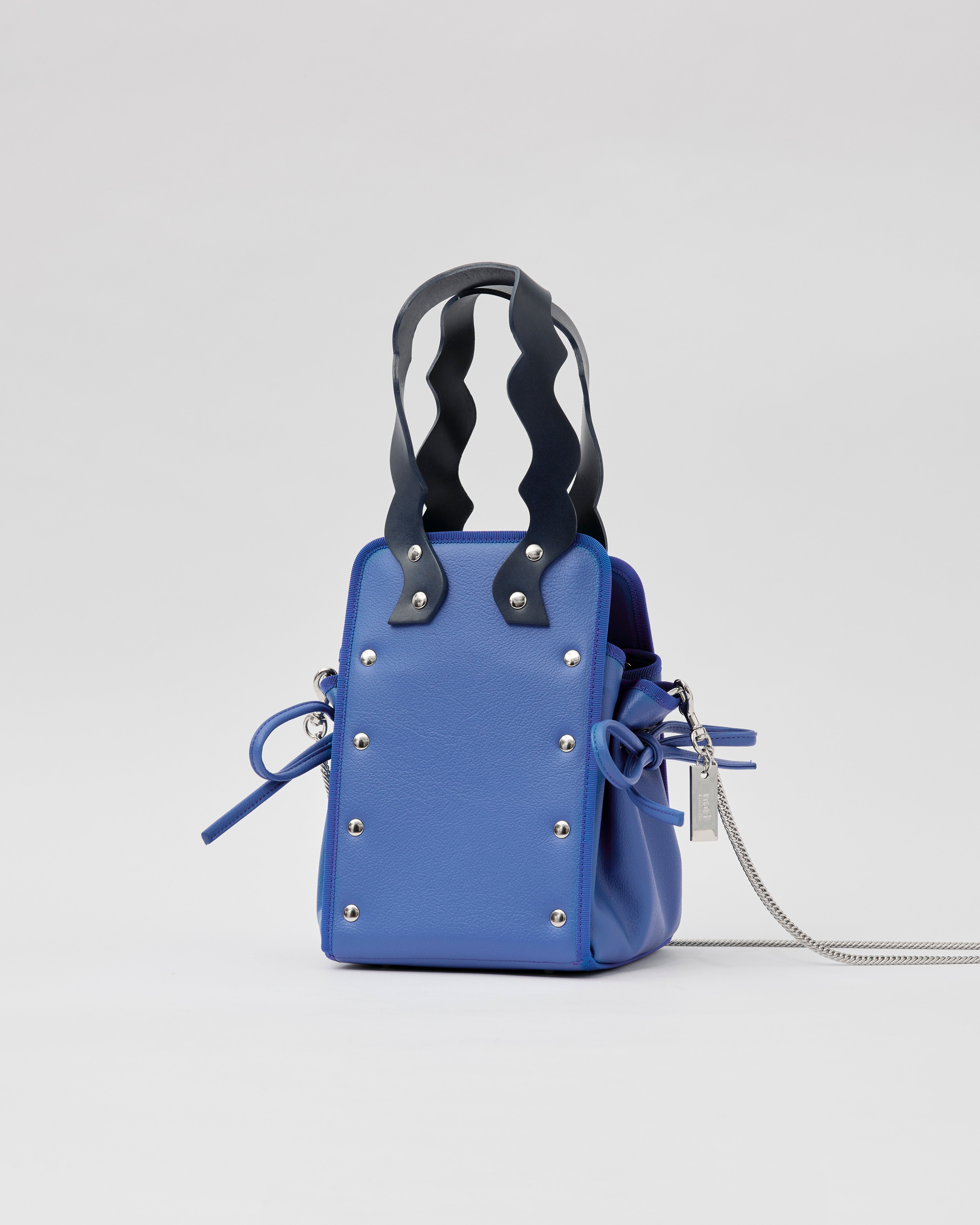 本革ハンドルの巾着型ハンドバッグ。サイドのドローストリングでシルエットを変化可能。500mlペットボトル対応サイズで内ポケット付き。取り外し可能なチェーンストラップでショルダー・クロスボディ両用。
