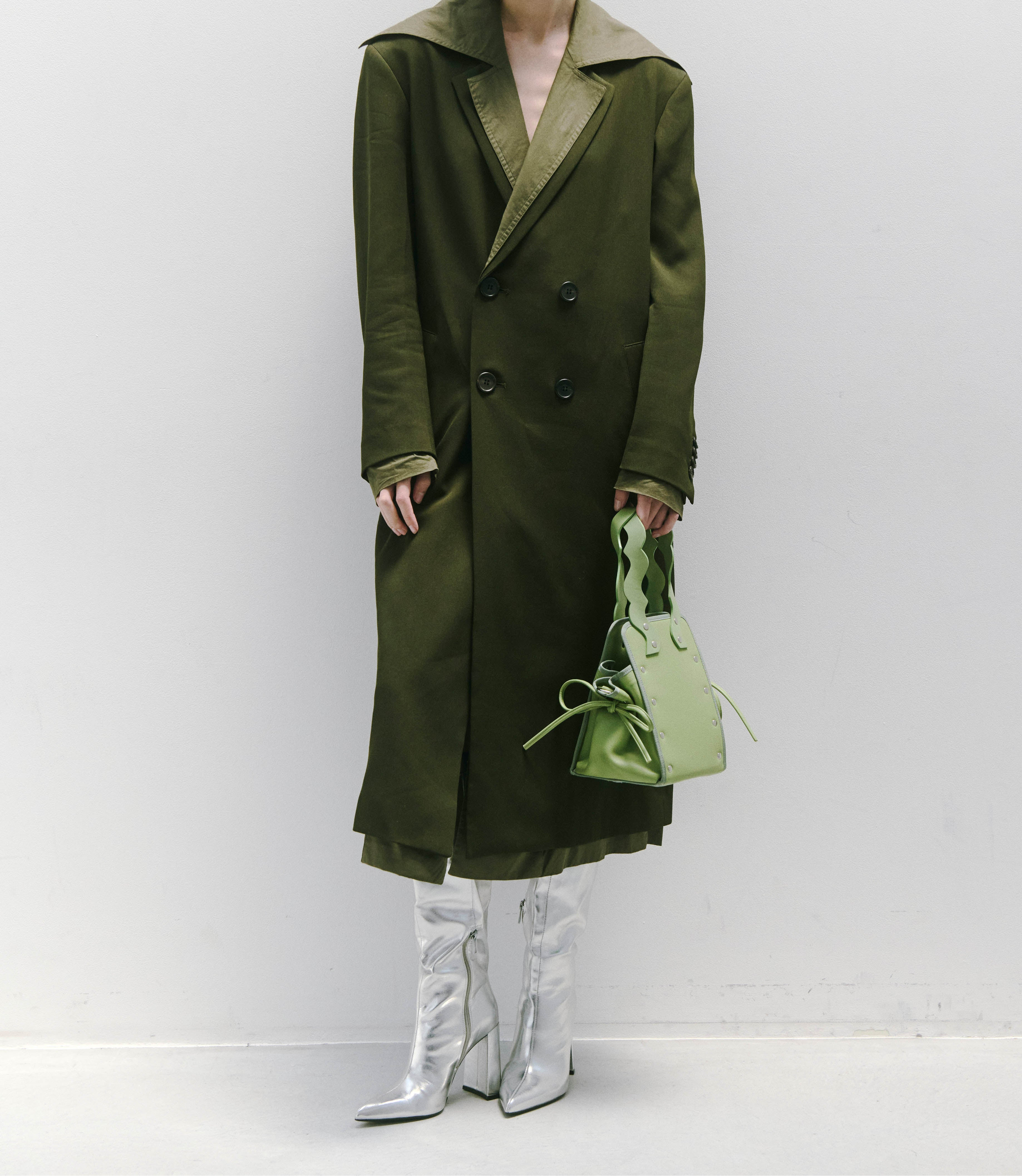 本革ハンドルの巾着型ハンドバッグ。サイドのドローストリングでシルエットを変化可能。500mlペットボトル対応サイズで内ポケット付き。取り外し可能なチェーンストラップでショルダー・クロスボディ両用。